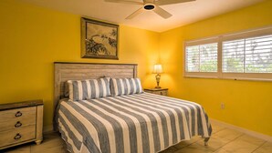 A bedroom with a bed, a nightstand, a ceiling fan, a window with blinds, and a wall-mounted picture. - Cheery Condo With Pool Access: 3 Miles to Beach! (Fort Myers)
