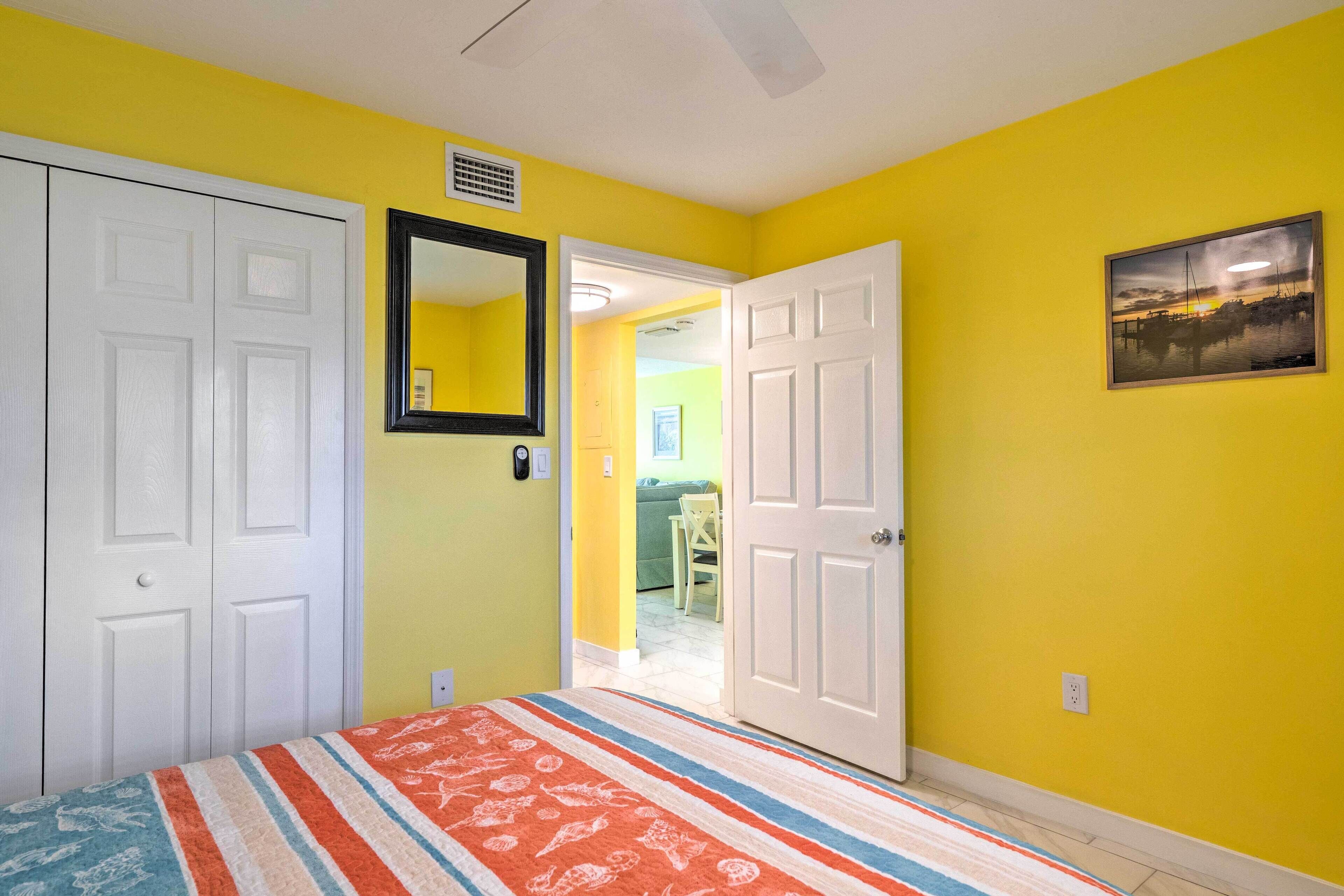 A bedroom with yellow walls, a striped bedspread, and two white doors.