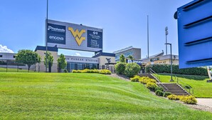 A stadium with a large sign advertising Panhandle Cleaning & Restoration, encova insurance, and Highmark. - Morgantown Home w/ Patio: Near WVU Football! (Morgantown)