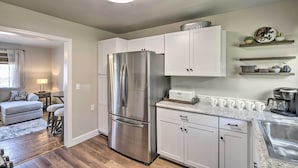 A modern kitchen with white cabinets, a stainless steel refrigerator, and a coffee bar with shelves above. - Morgantown Home w/ Patio: Near WVU Football! (Morgantown)