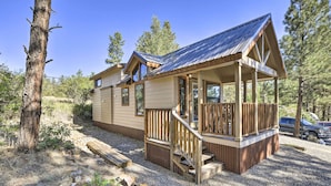 A cabin with a wooden deck and a covered porch, surrounded by trees. - Roomy Pagosa Springs Tiny Cabin: 1 Mi to Downtown (Pagosa Springs)