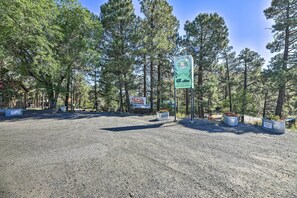 A parking area with a sign for Dragon's Den RV Park, surrounded by tall pine trees. - Roomy Pagosa Springs Tiny Cabin: 1 Mi to Downtown (Pagosa Springs)