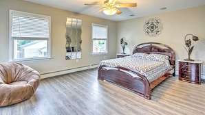 A bedroom with a wooden bed, a ceiling fan, a large mirror, and a bean bag chair. - Family-friendly Keansburg Home: Walk to Beach! (Keansburg)