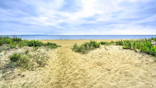 A sandy beach with a clear sky and a view of the ocean. - Family-friendly Keansburg Home: Walk to Beach! (Keansburg)