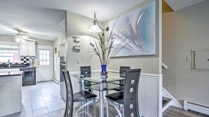 A modern kitchen with a glass dining table, black chairs, and a large abstract painting on the wall. - Family-friendly Keansburg Home: Walk to Beach! (Keansburg)