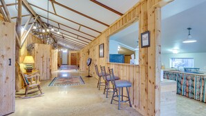A wooden interior with a long hallway, wooden chairs, a rug, and a kitchen area with a counter and sink. - Black Hills Vacation Rental 25 Mi to Mt Rushmore! (Hermosa)