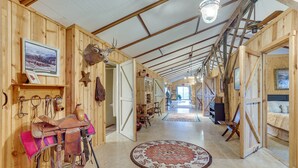 A spacious interior with wooden walls, a mounted deer head, a saddle, and a large rug. - Black Hills Vacation Rental 25 Mi to Mt Rushmore! (Hermosa)
