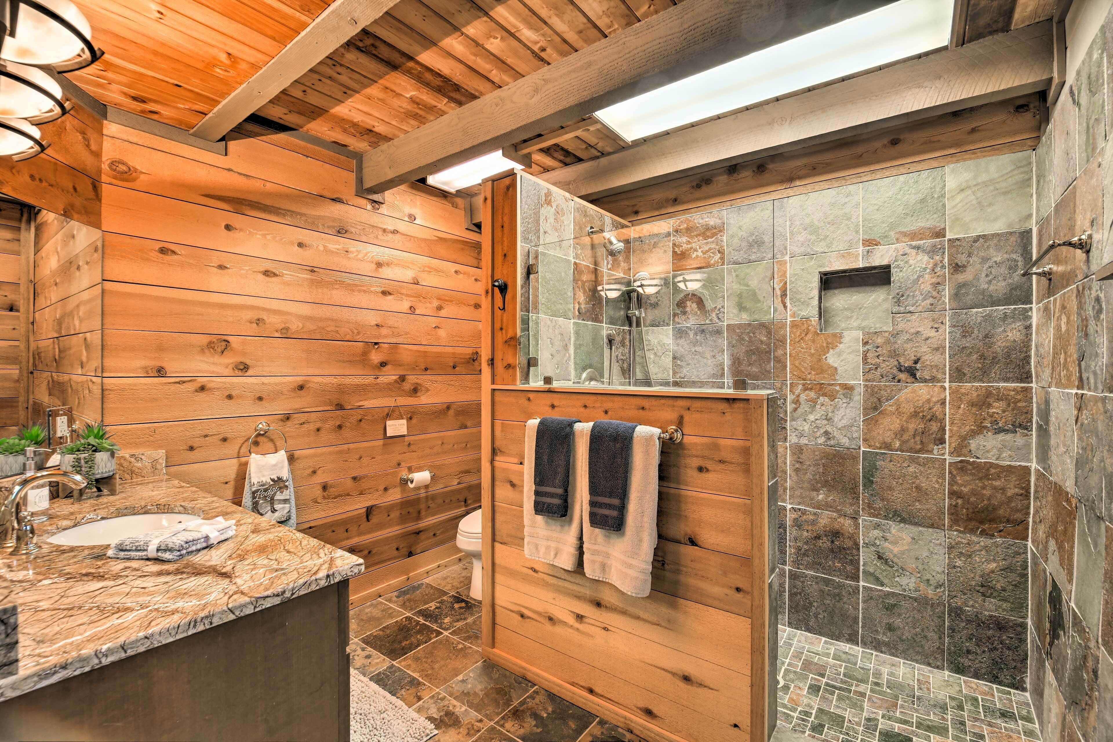 A wooden interior with a bathroom featuring a sink, towel rack, and shower area.