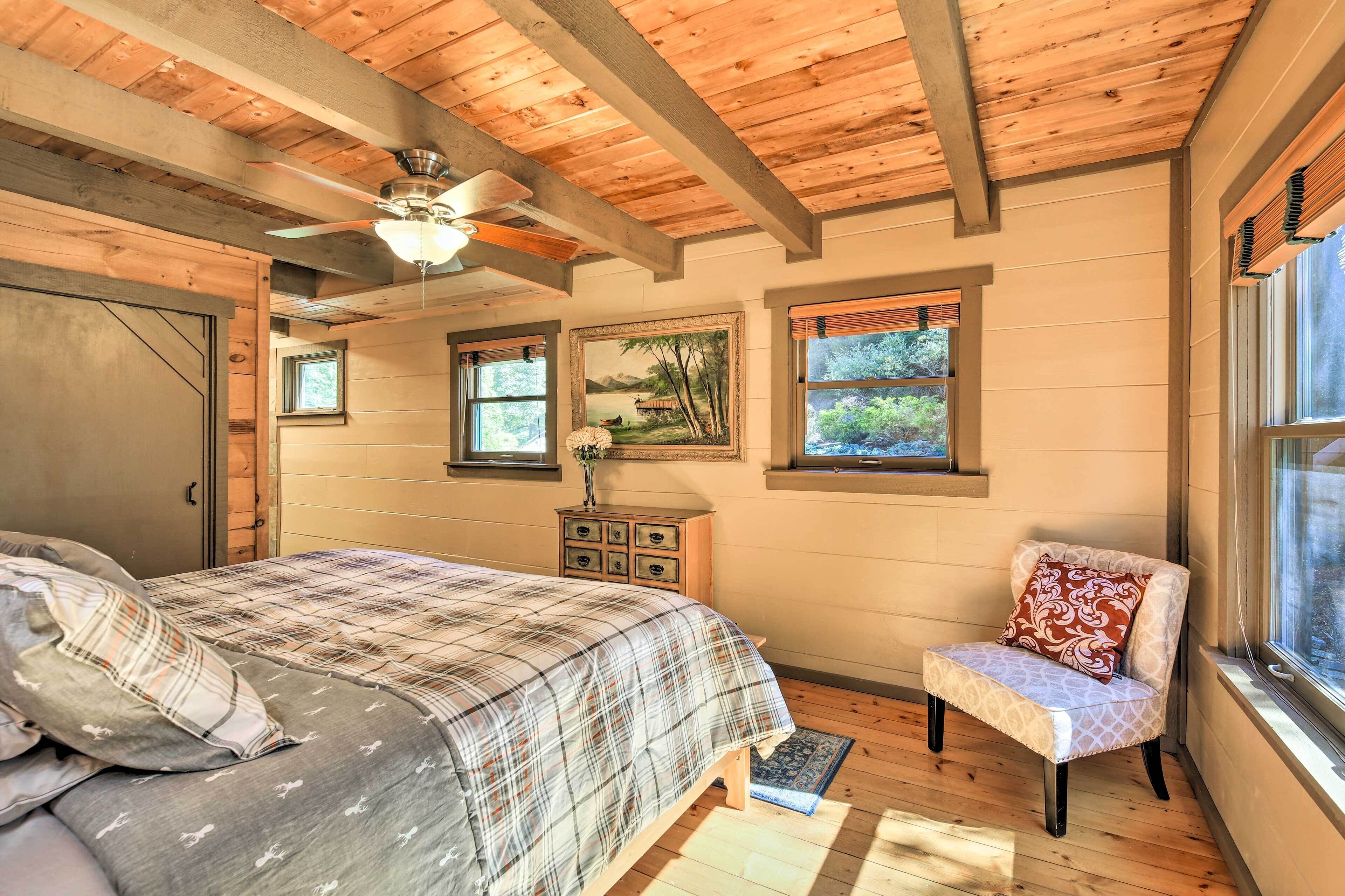A bedroom with a bed, a chair, a dresser, and a ceiling fan.