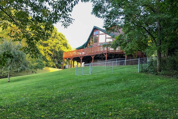 A wooden cabin with a balcony, surrounded by trees and a fenced yard. - 9 Mi to Sugar Mountain: Stunning Cabin w/ Views (Banner Elk)