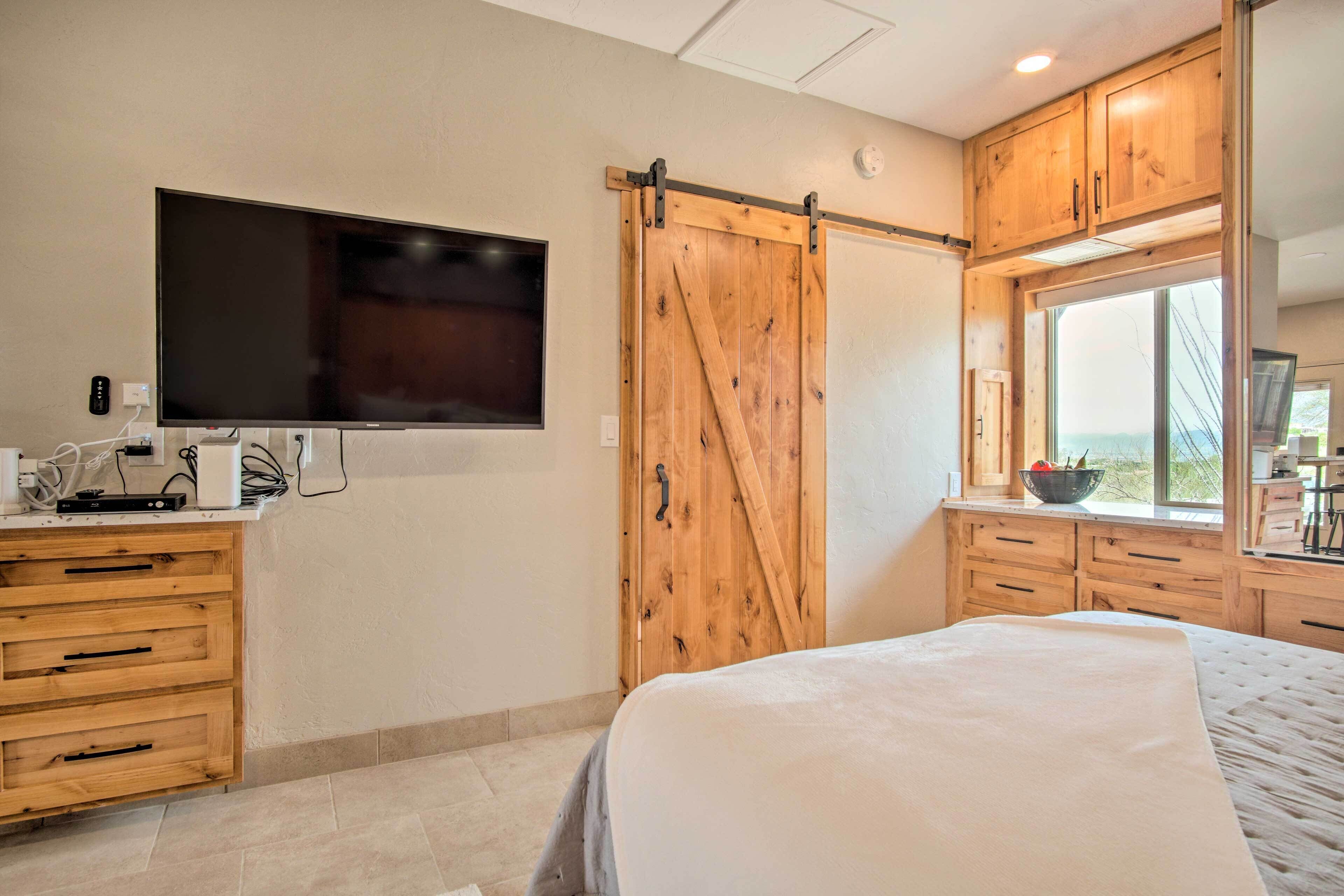 A bedroom with a large bed, wooden cabinets, a television, and a sliding barn-style door.