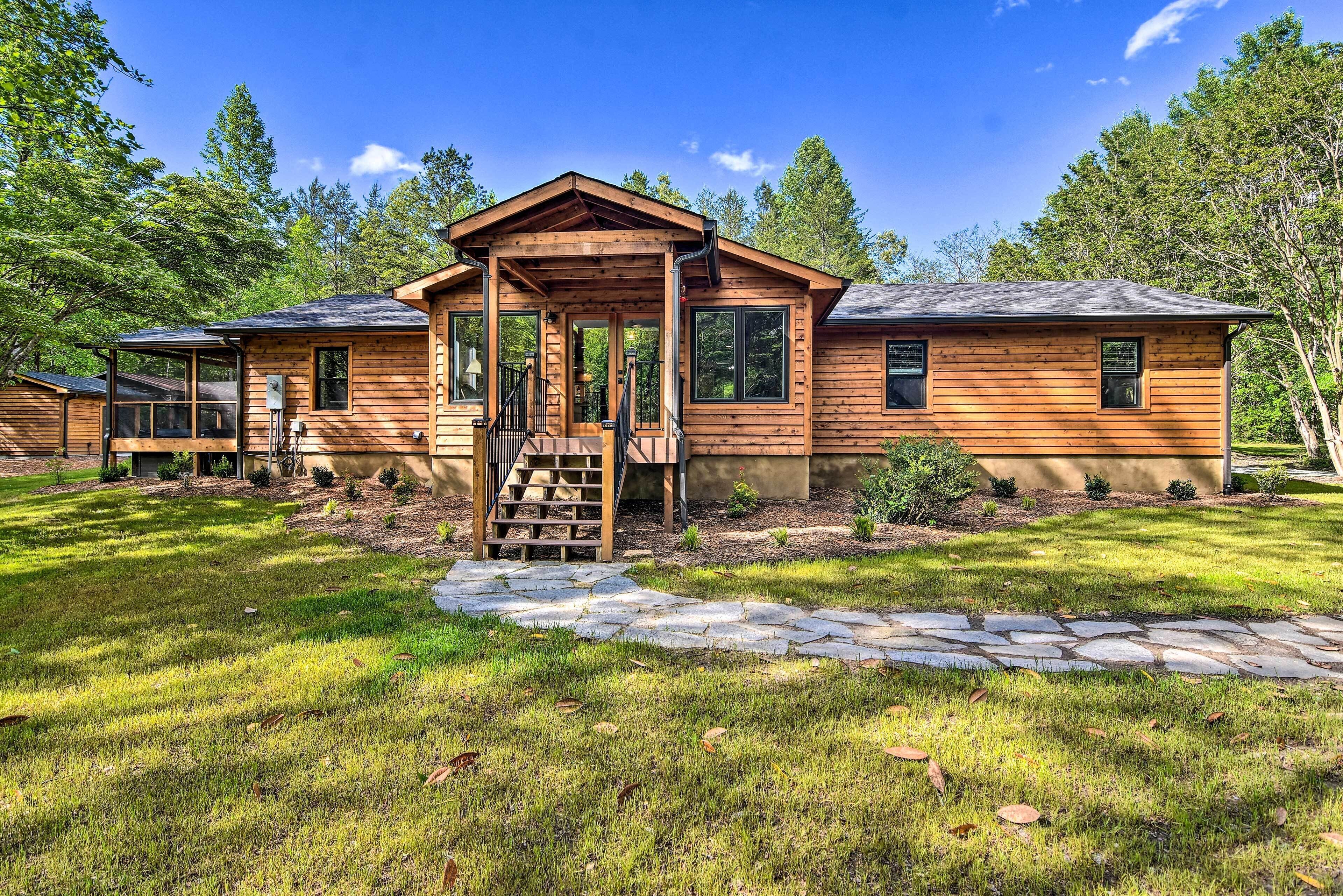 A wooden cabin with a covered porch, stone pathway, and a well-maintained lawn.