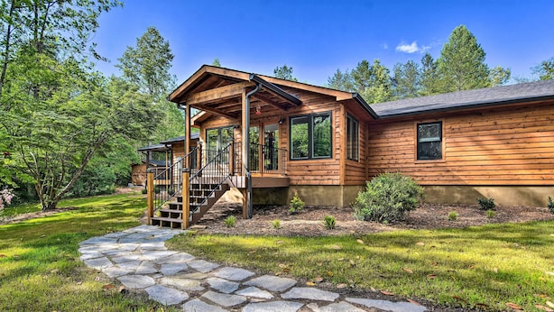 A wooden cabin with a stone pathway leading to a porch, surrounded by trees and a well-maintained lawn. - Rustic Sunset Escape on 67 Acres: Outdoor Kitchen (Sunset)