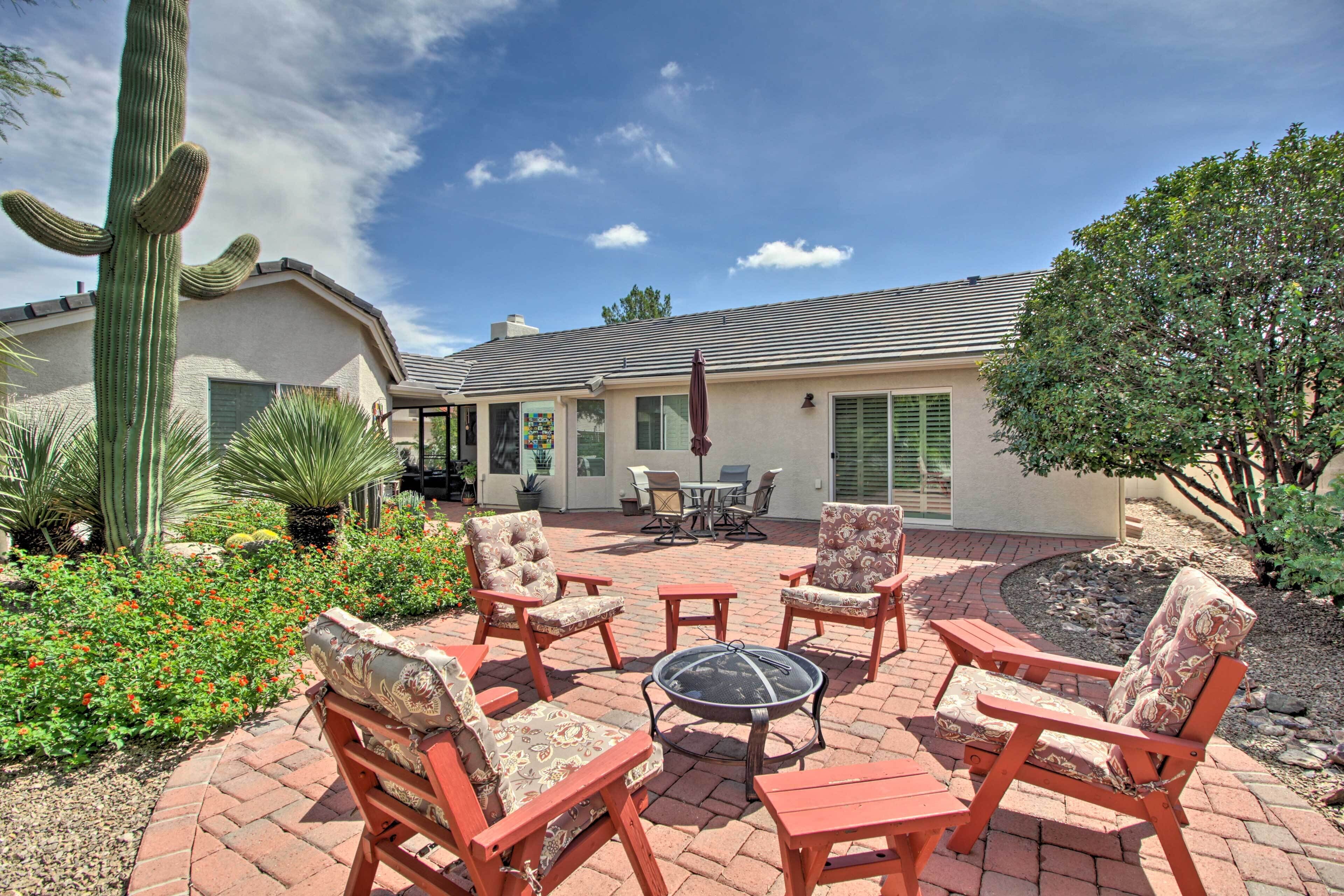 A patio with outdoor furniture, a fire pit, and a cactus.