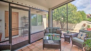 A sunlit patio with a glass door leading to a covered area, wicker furniture, and potted plants. - AZ Home w/ Resort-style Amenities & Mtn View! (Saddlebrooke)