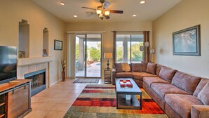 A living room with a fireplace, a sofa, a coffee table, and a television. - Scottsdale Home - Mtn Views, Pool, Near Westworld! (Scottsdale)