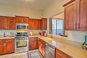 A modern kitchen with wooden cabinets, stainless steel appliances, and a large window providing natural light. - Scottsdale Home - Mtn Views, Pool, Near Westworld! (Scottsdale)