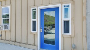 Un bâtiment avec une porte bleue, un revêtement de couleur beige et deux fenêtres.