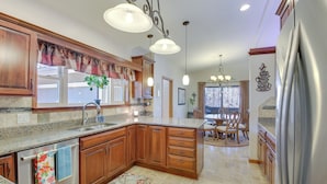 A kitchen with wooden cabinets, granite countertops, and a stainless steel refrigerator.