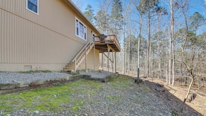 A two-story house with a wooden deck and a staircase leading to a balcony.
