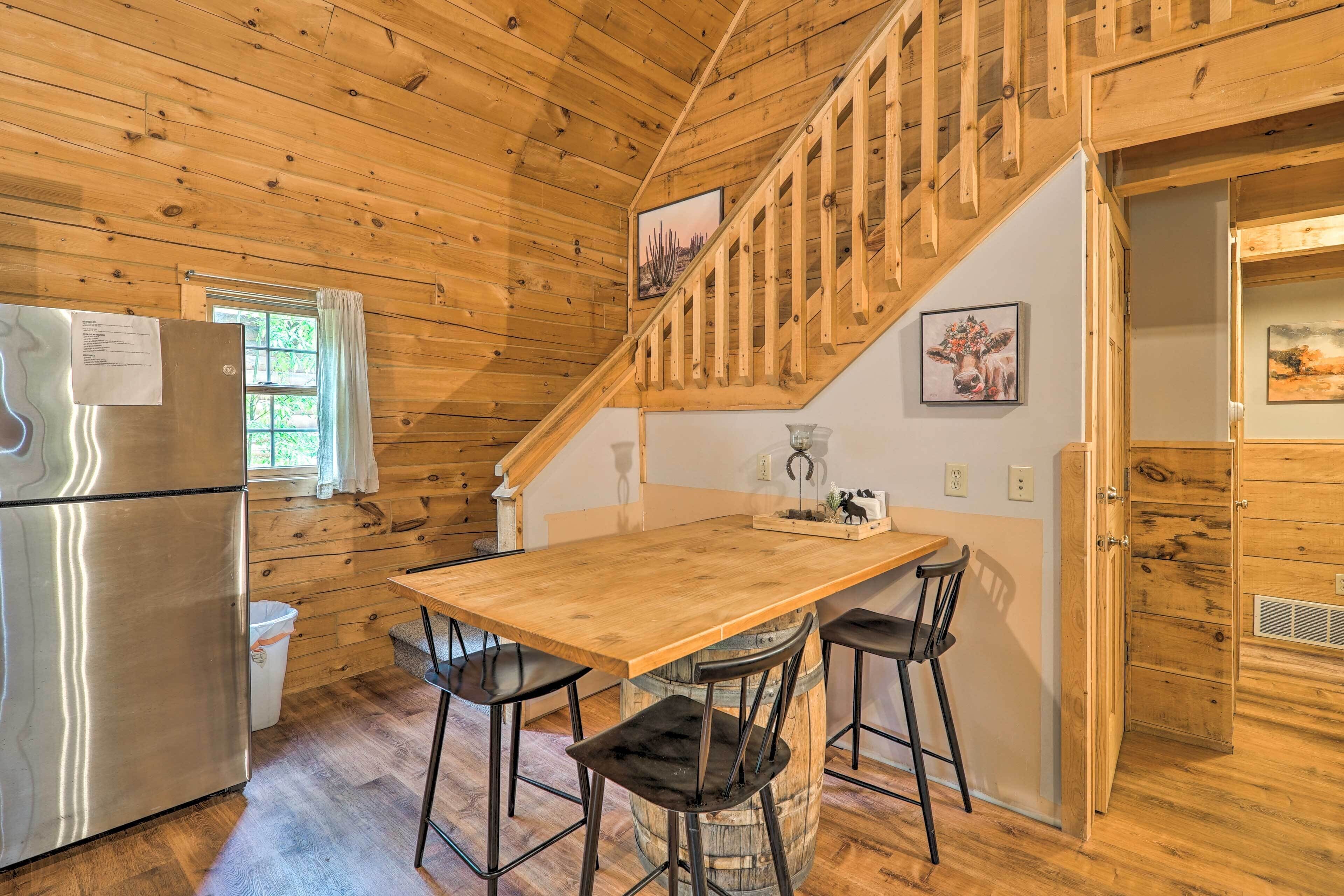 A wooden interior with a kitchen area, a wooden staircase, and a dining table with chairs.
