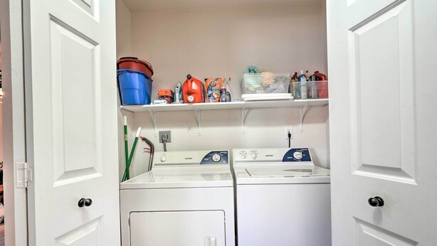 A laundry room with two washing machines, a dryer, and shelves above containing cleaning supplies and a blue bucket. - Scottsdale Home: Pool Access, 13 Mi to Phoenix (Scottsdale)