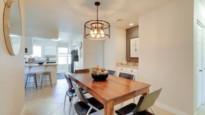 A dining area with a wooden table, black chairs, a chandelier, and a kitchen in the background. - Scottsdale Home: Pool Access, 13 Mi to Phoenix (Scottsdale)