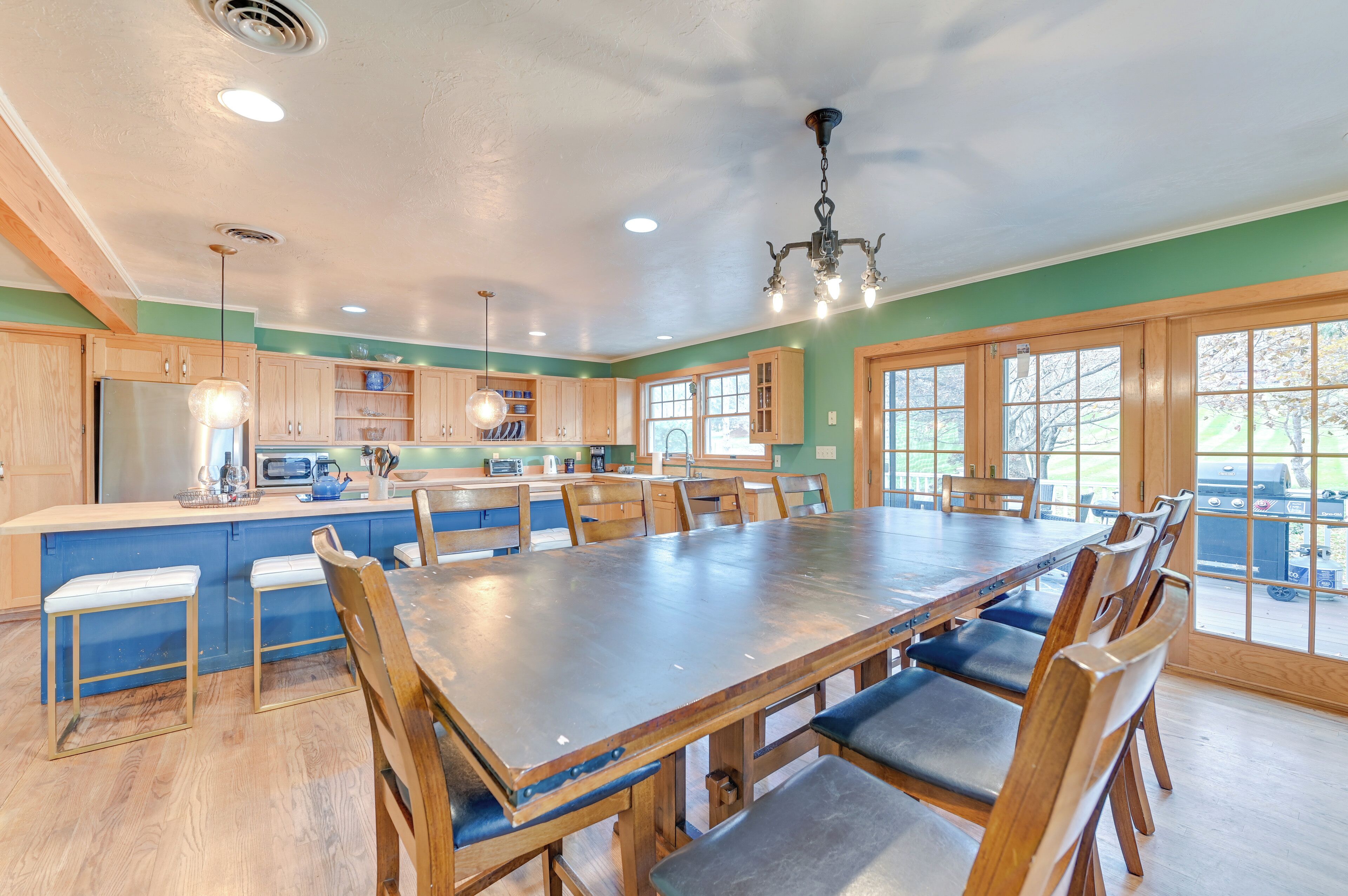 A spacious kitchen with wooden cabinets, a large dining table, and bar stools.