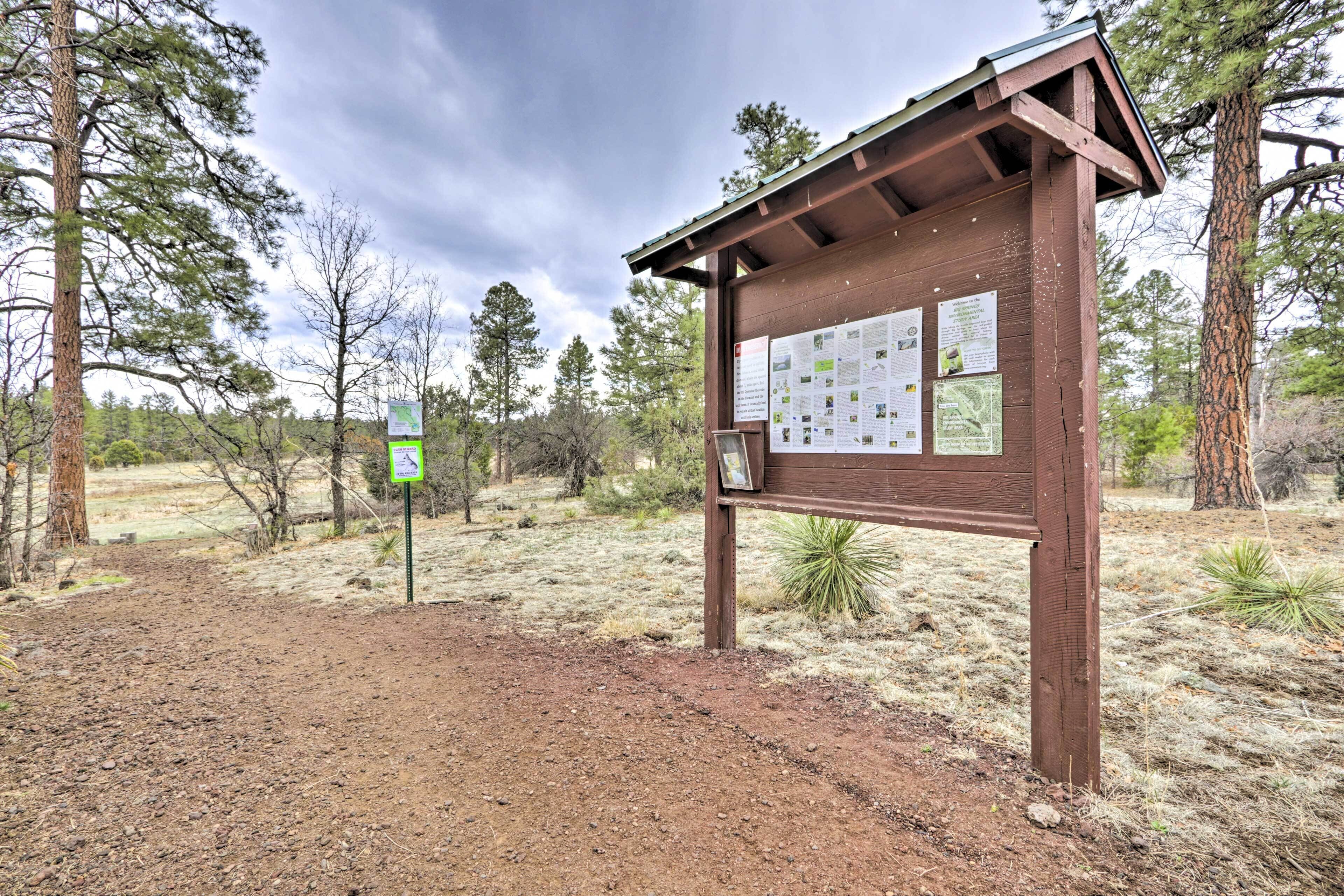 A wooden information board with maps and notices in a natural setting.