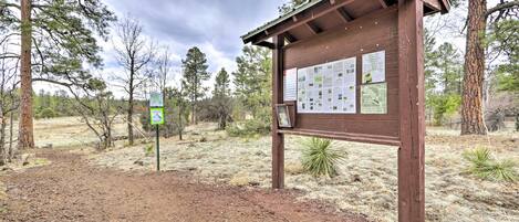 A wooden information board with maps and notices in a natural setting.