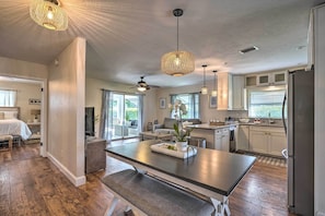 A spacious kitchen with a central island, pendant lighting, and a refrigerator.