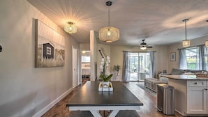 A modern kitchen with a central island, pendant lighting, and a dining area with a bench. - Naples Oasis w/ Screened Pool, Bike to Beach! (Naples)