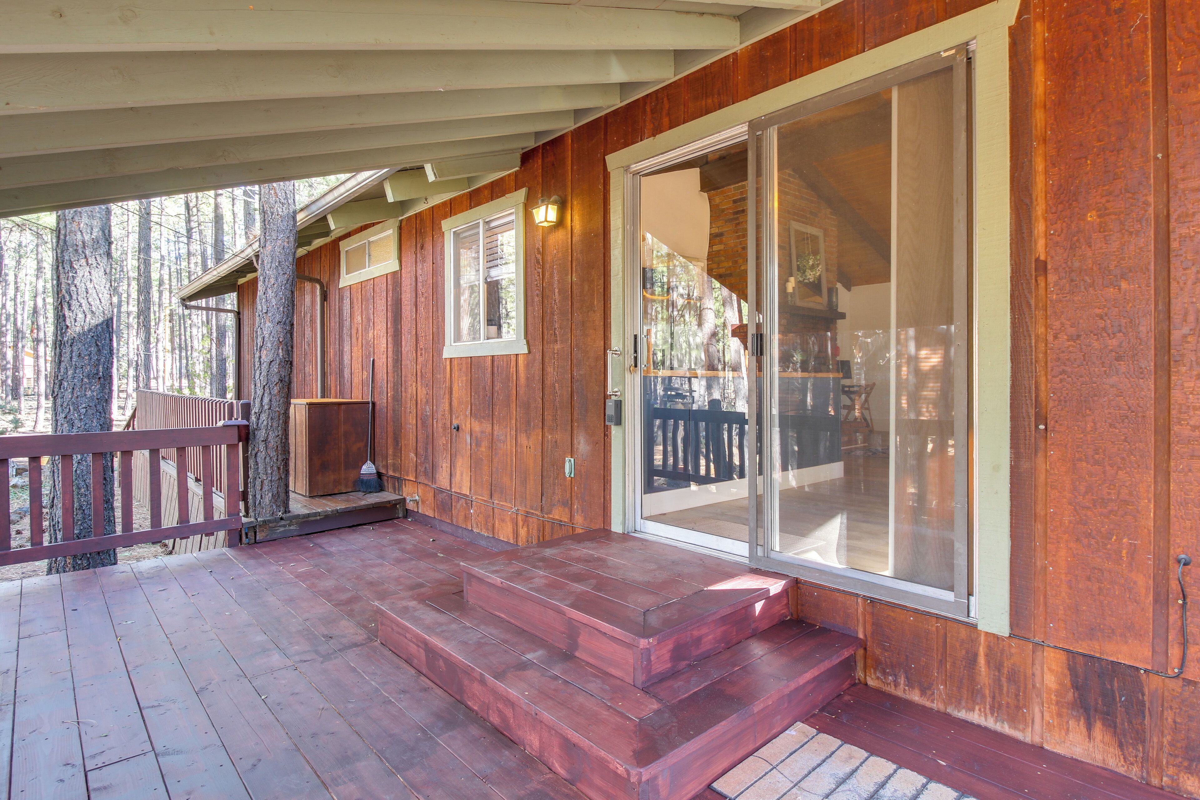 A wooden cabin with a covered porch, large sliding glass doors, and a wooden deck.