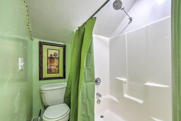 Un baño con inodoro, bañera y cortina de ducha.
