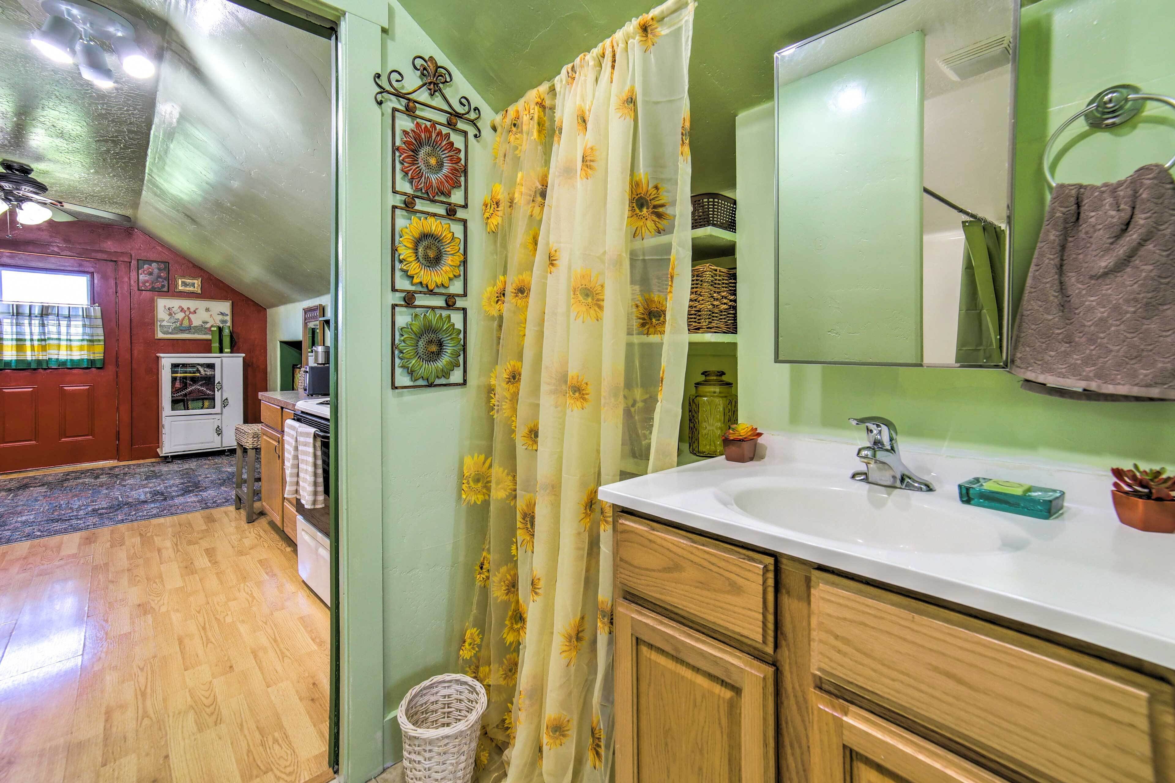 A bathroom with a sink, mirror, and shower curtain with sunflowers.