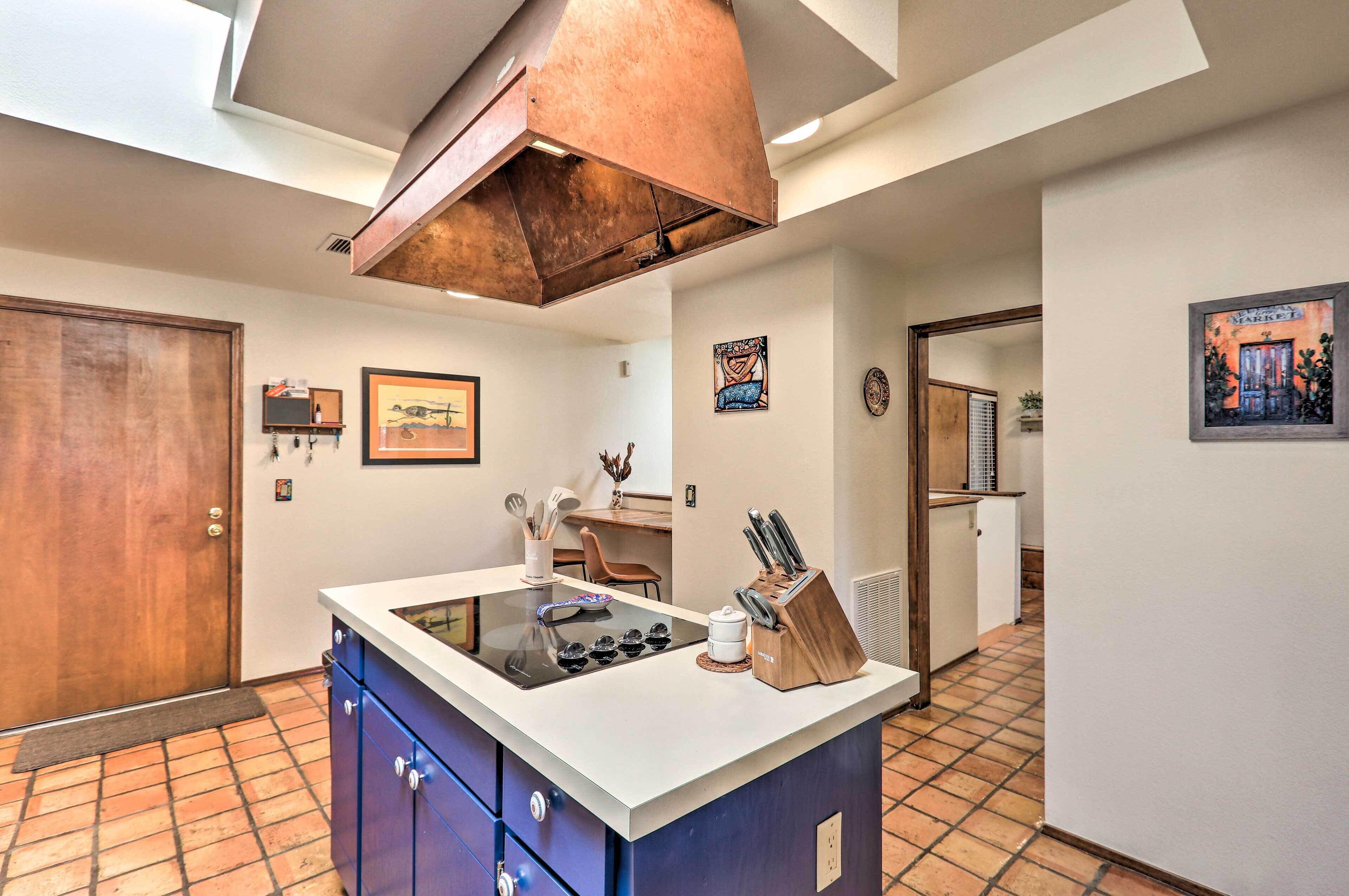 A kitchen with a central island, a wooden cabinet, a sink, and a copper range hood.