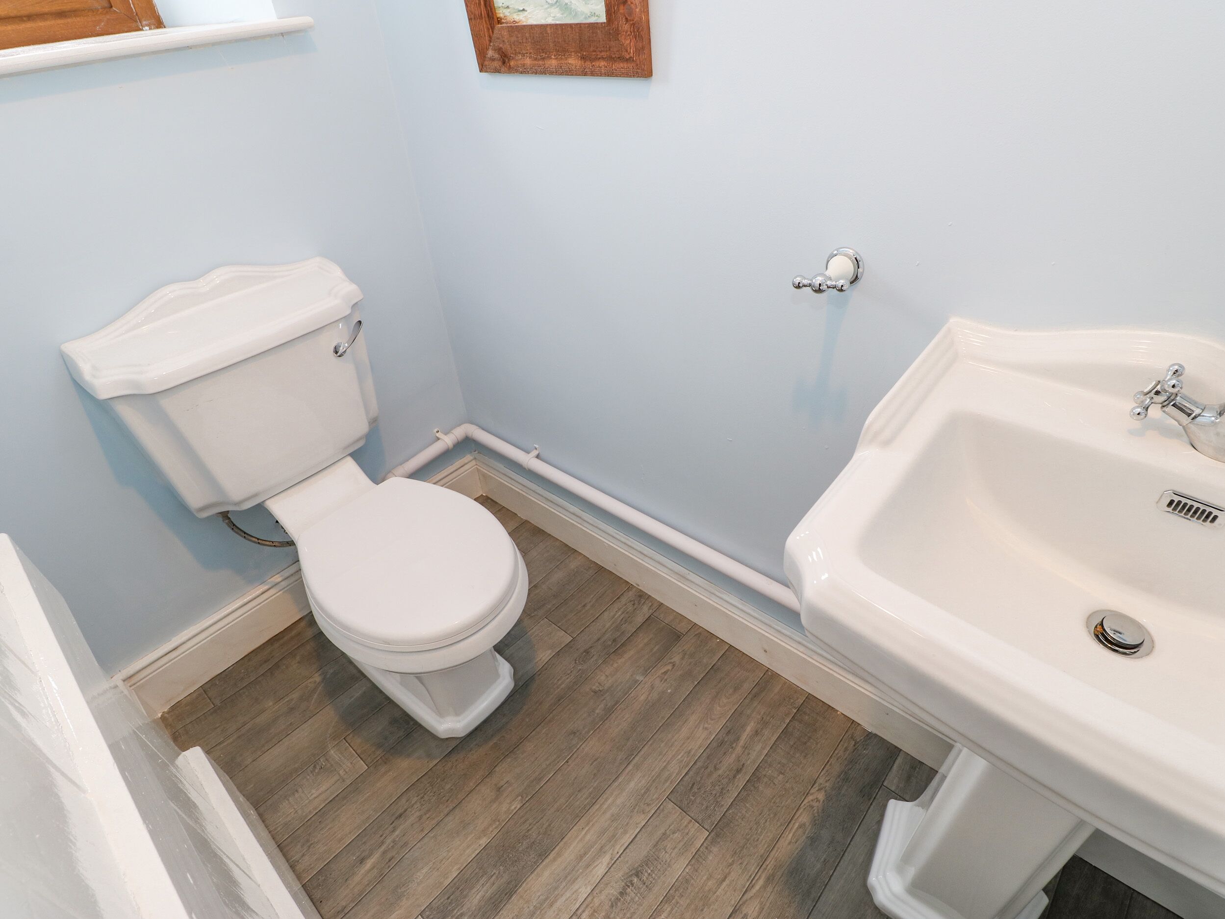 Un baño con inodoro, lavamanos y suelo de madera.
