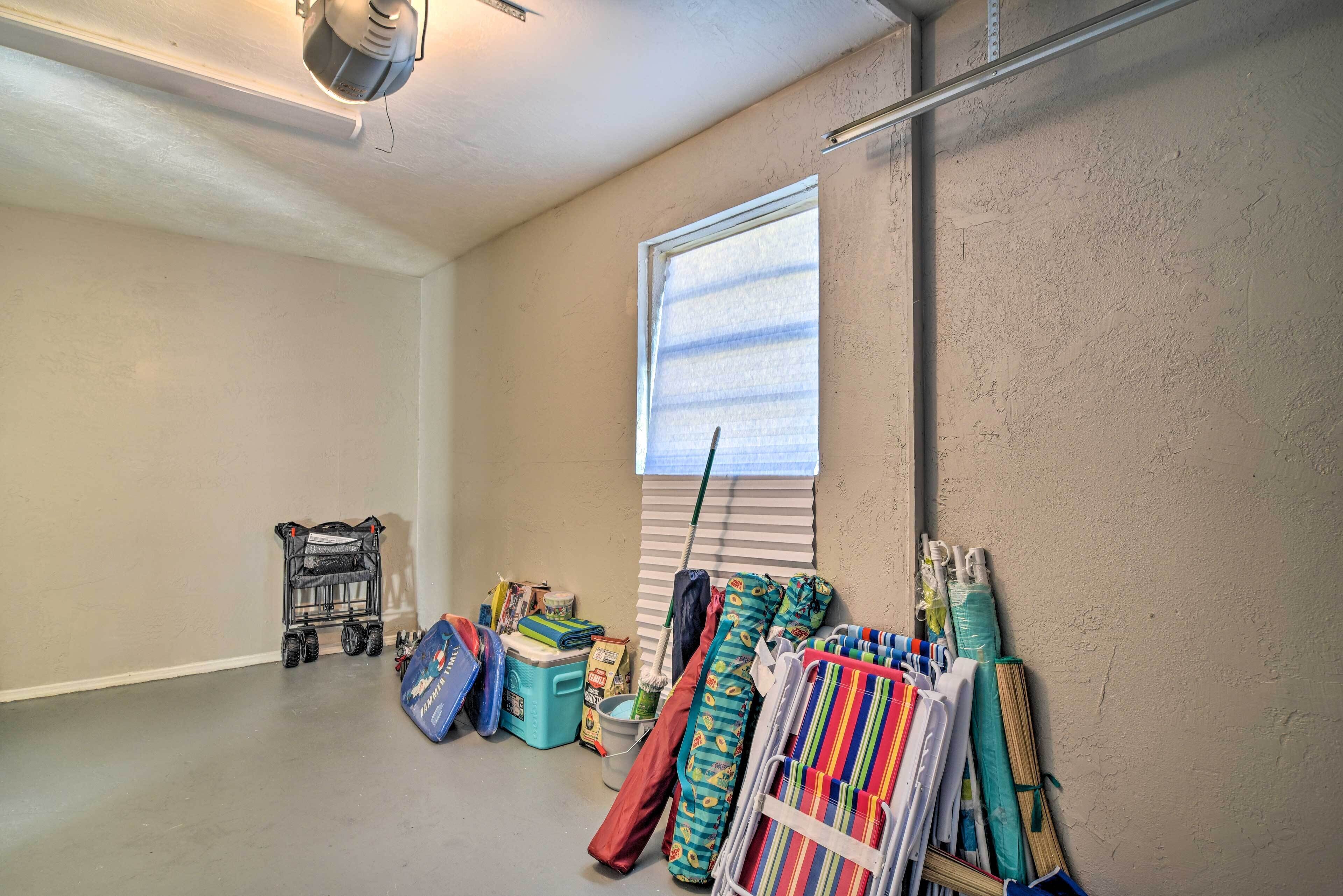 A garage with a window, a broom, cleaning supplies, and a stroller.