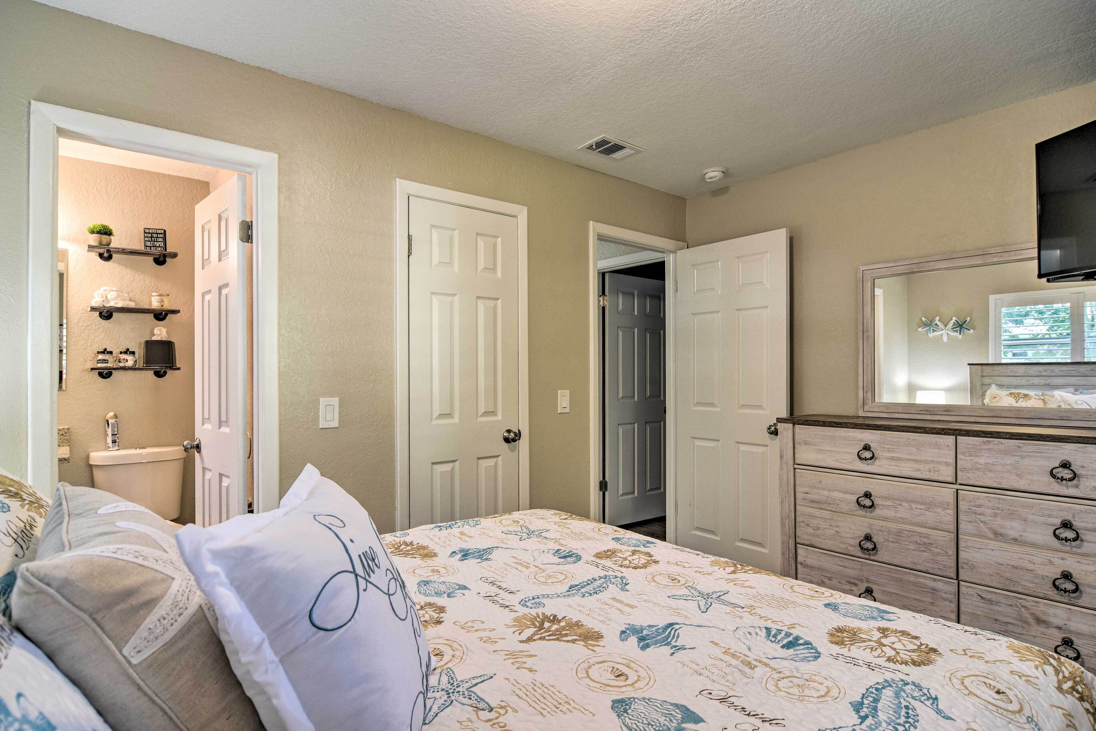 A bedroom with a bed, dresser, and a television mounted on the wall.