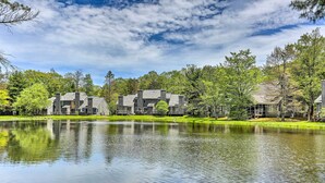 A lakeside property with multiple buildings, a calm lake, and surrounding trees.