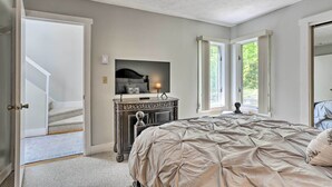 A bedroom with a bed, a dresser, a television, and a window.