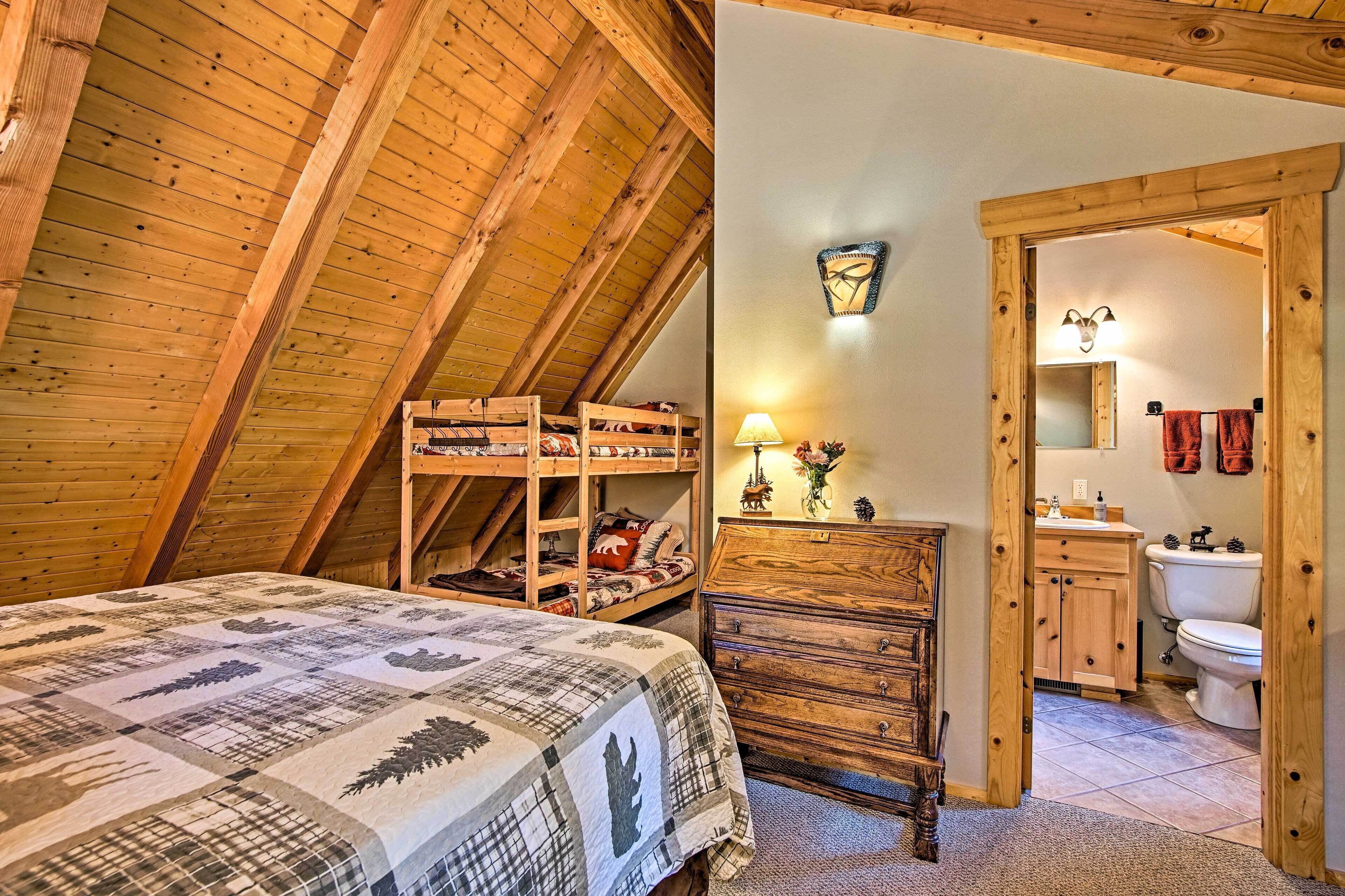 A cozy attic bedroom with a bed, wooden bunk beds, and a dresser.