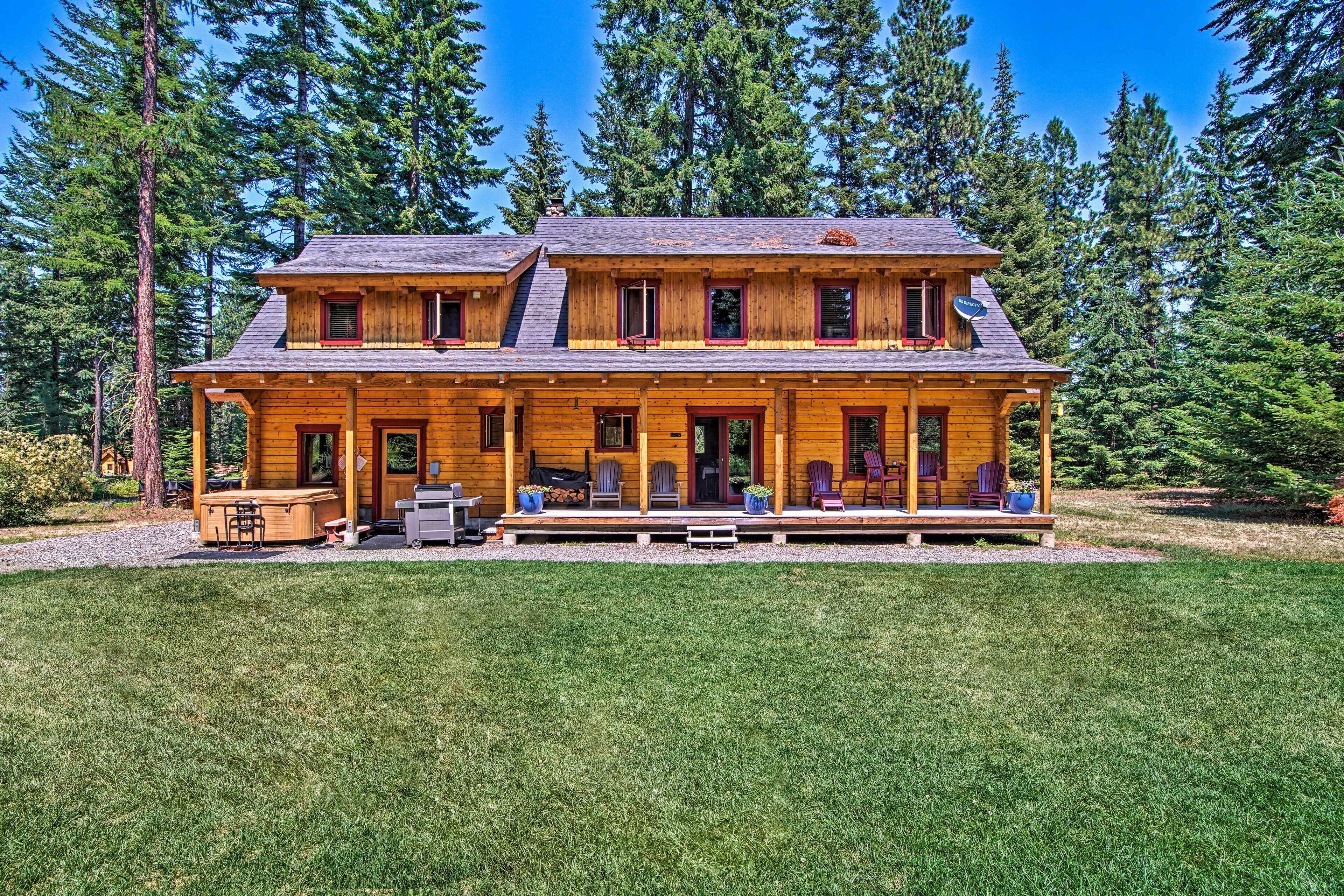 A two-story log cabin with a porch, outdoor seating, and a satellite dish.