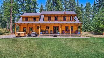 A two-story log cabin with a porch, outdoor seating, and a satellite dish.