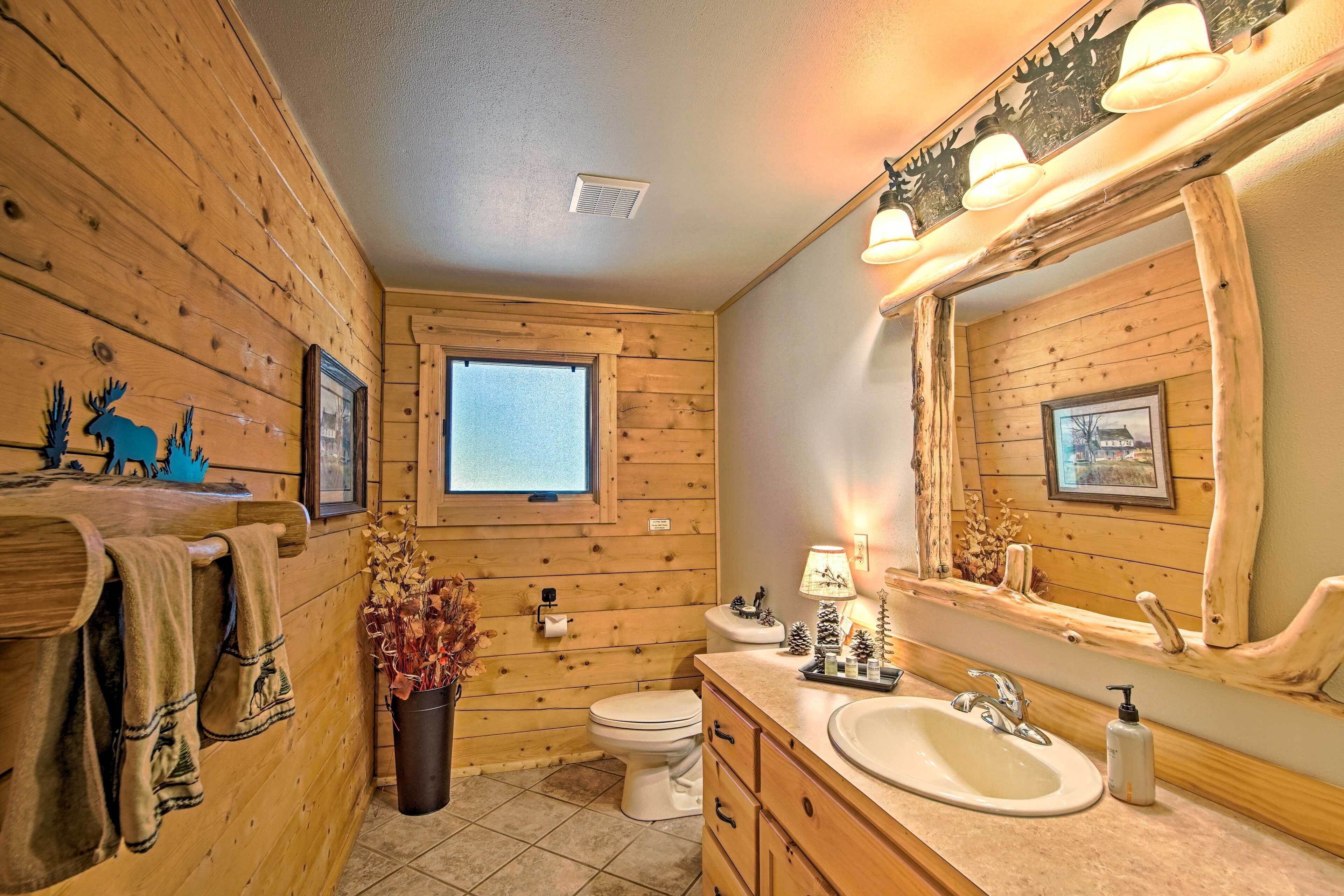 Un baño de cabaña de madera con ventana, lavamanos e inodoro.