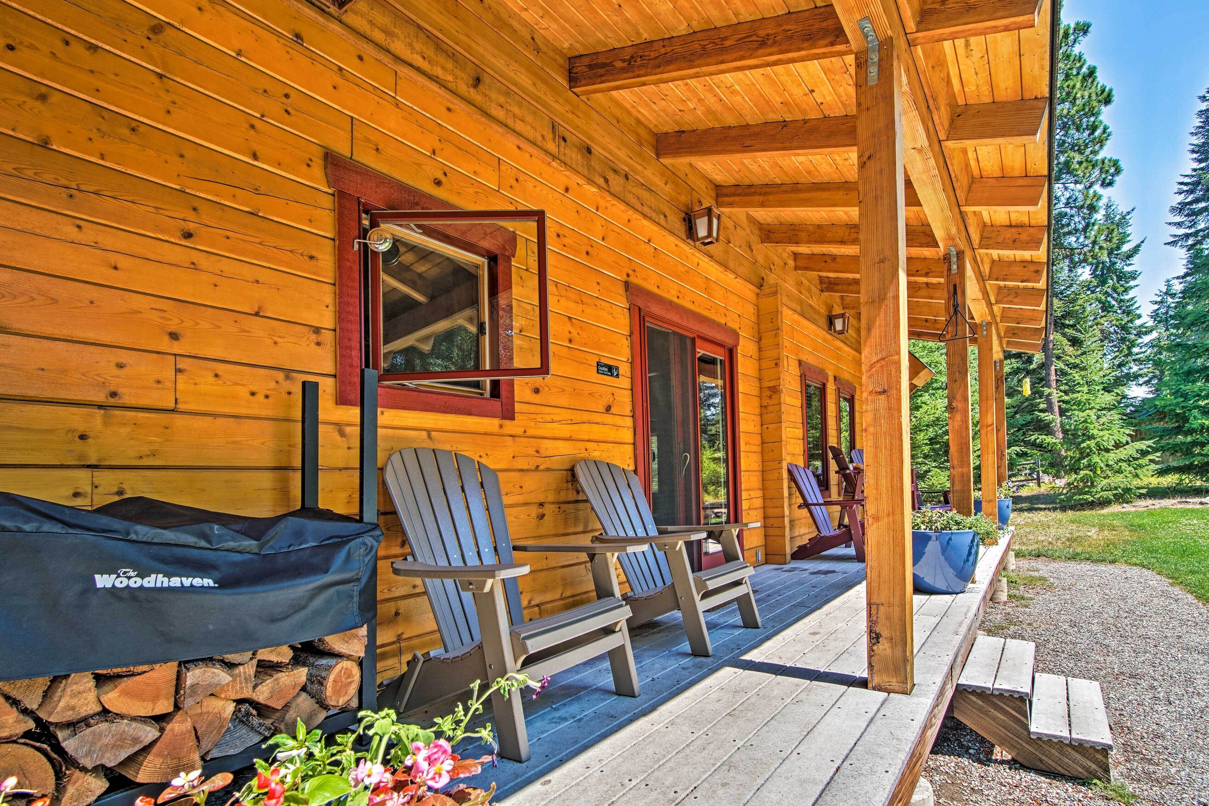 A wooden cabin with a porch, two Adirondack chairs, and a grill cover labeled 'The Woodhaven.'