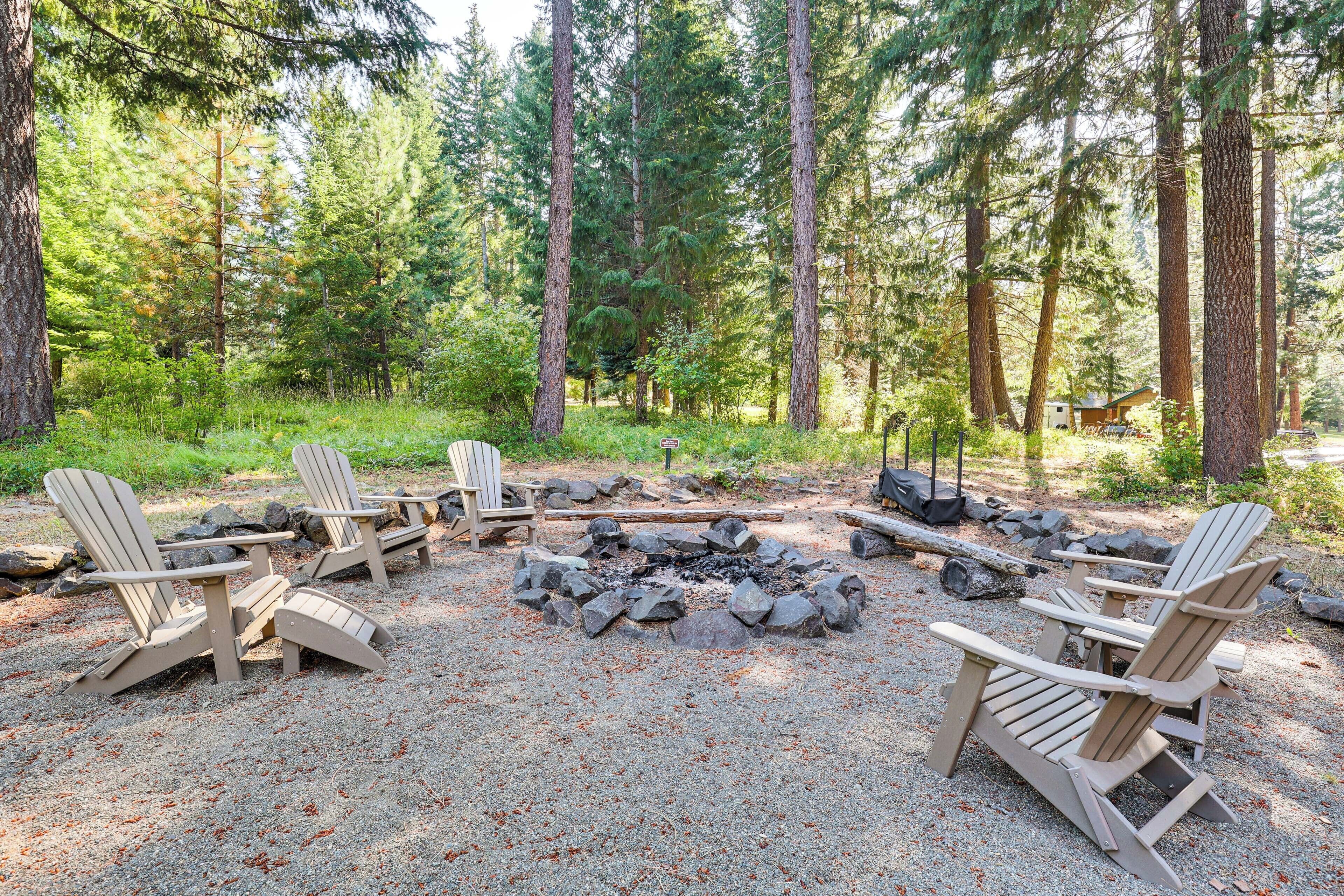 Ein bewaldeter Campingplatz mit Adirondack-Stühlen um ein Lagerfeuer.
