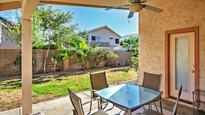 A covered patio with a glass table and chairs, a ceiling fan, and a view of a residential area with a house and greenery. - 5 Mi to Spring Training: Family Home w/ Grill (Peoria)