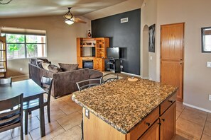 A modern kitchen with granite countertops, wooden cabinets, a dining area with a table and chairs, and a living room with a sofa and chairs. - 5 Mi to Spring Training: Family Home w/ Grill (Peoria)