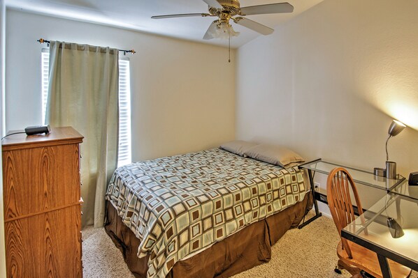 A bedroom with a bed, a wooden dresser, a desk with a chair, a ceiling fan, and a window with curtains. - 5 Mi to Spring Training: Family Home w/ Grill (Peoria)